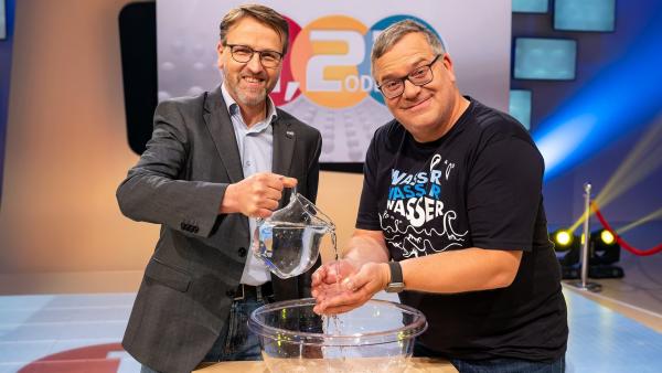 Ökologe Dr. Martin Zimmer steht mit Elton an einem hüfthohen Tisch. Martin Zimmer lässt Elton aus einer Karaffe Wasser über die Hände laufen. Auf dem Tisch steht eine große Schüssel, in dem das Wasser aufgefangen wird.