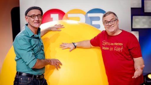 superkräfte-der-sonne | Rechte: ZDF "1, 2 oder 3 - Superkräfte der Sonne": Solarexperte Rolf Behringer und Elton stehen im Studio vor einem großen gelben Ball.