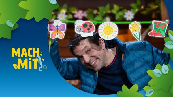 Juri schaut lachend unter der MACH MiT! Frühlingsgirlande hervor.
