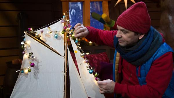 Juri schmückt ein Schiff mit Lichtern nach einer griechischen Tradition zu Weihnachten.