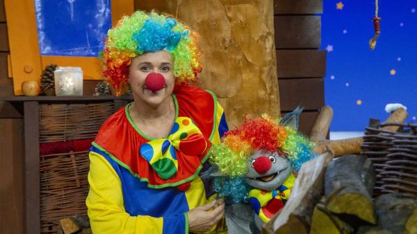 Singa und Fidi sitzen im Baumhaus und tragen beide Clownskostüme und Perrücken in Regenbogenfarben.