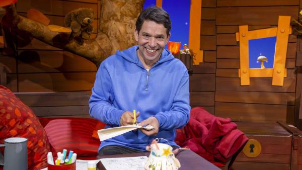 Juri schneidet mit der Schere die MACH MiT!-Bastelvorlage aus. Es ist eine Laterne.