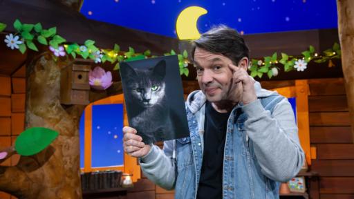 Juri hält ein Bild von einer Katze hoch und schaut wissend.