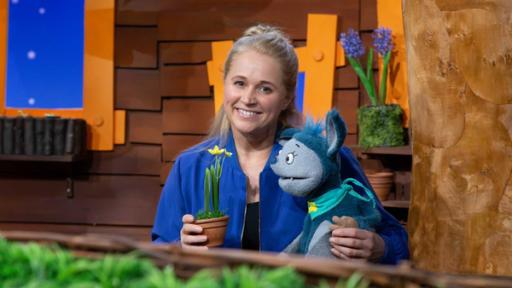 Fidi und Singa sitzen im Baumhaus. Singa hält eine Frühlingsblume in der Hand.