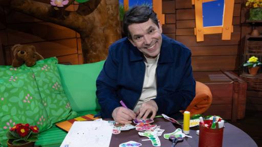 Juri sitzt im Baumhaus und malt für die MACH MiT!-Frühlingsgirlande einen Schmetterling bunt aus.
