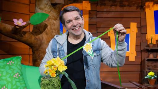 Juri bastelt die MACH MiT!-Frühlingsgirlande. Er zeigt eine gelbe Blume.