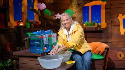 Singa sitzt im Baumhaus und wäscht sich die Hände mit Wasser aus Kanistern.