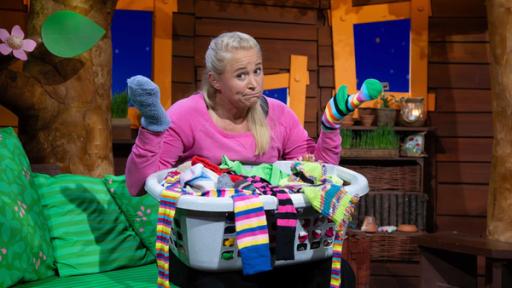 Rechte: KiKA Singa sitzt im Baumhaus. Vor ihr steht ein Korb voller Socken.