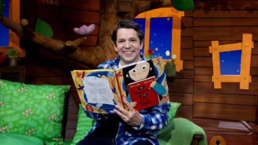 Juri hält ein Kinderbuch in den Händen und liest darin.