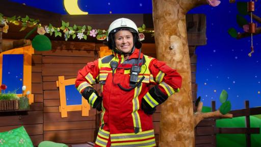 Rechte: KiKA Singa steht selbstbewusst in kompletter Feuerwehrmontur im Baumhaus.