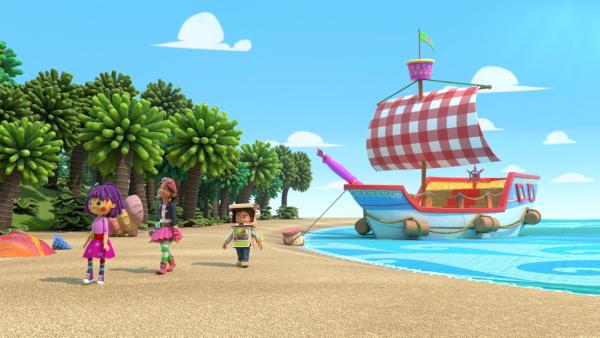 Bitz, Bob und Fleur laufen am Strand der Weit-weit-weg-Insel. Im Hintergrund sind Palmen und im Wasser liegt das Segelschiff an.