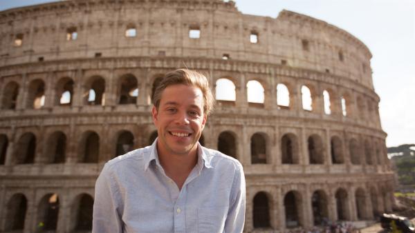 Tobi steht vor dem Colosseum in Rom und lächelt in die Kamera.