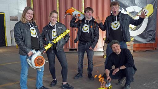 Feuerbälle, Konfetti XXL & springende Steine | Rechte: ZDF In der Checkpoint-Halle stehen die Testteamer Lisa, Antonia, Felix und Kenneth mit selbstgebauten Laubbläsern in der Hand. Tommy Scheel sitzt vor ihnen in der Hocke; vor ihm ein angezündeter Volleyball.