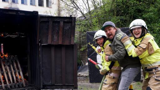 Zwei Jugendliche in Feuerwehrsmontur halten Feuerwerkskörper.