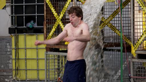 Auf einen oberkörperfreien Mann wird Wasser gekippt.