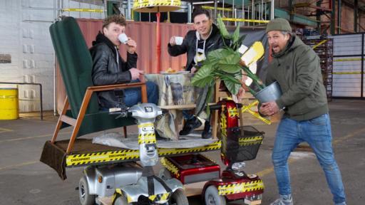 Monsterscooter, Linkshänder und ein Absturz | Rechte: ZDF Im Bild befinden sich zwei Senioren-Scooter, auf denen längs eine Platte angebracht ist. Darauf stehen zwei Sessel, in denen zwei Checkpoint-Tester gemütlich Tee trinken. Tommy Scheel steht rechts im Bild und hält eine Zimmerpflanze in der Hand.