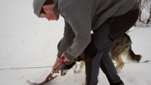 H wie Hundeklo | Rechte: BR / Bewegte Zeiten Filmproduktion GmbH / René Goergens Max steht im Schnee mit einer Schaufel in den Händen. Hinter ihm ist ein Hund zu sehen.