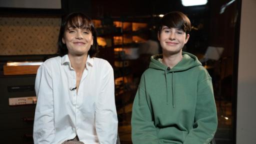 "Dein Song"-Kandidatin Leni (16) und Musikpatin Lotte sitzen nebeneinander in einem Tonstudio. Dabei blicken sie freundlich lächelnd in die Kamera.