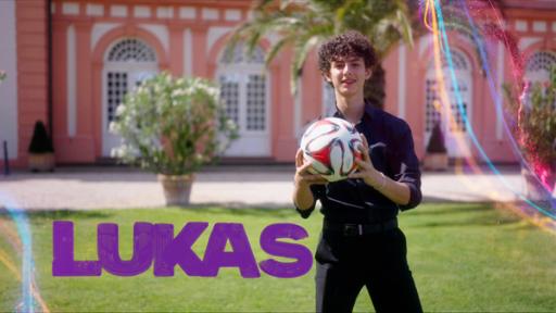 Lukas hält einen Fußball in der Hand, hinter ihm Schloss Biebrich.