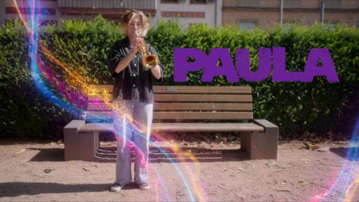 Paula spielt ein Waldhorn, hinter ihr ein Busch und eine Parkbank.