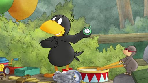 Rabe Socke hält eine Uhr in die Luft, neben ihm schlägt ein kleiner Maulwurf auf eine Trommel