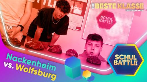 Rechte: KiKA/Bavaria Entertainment Rechts ein Schüler. Er schaut knapp über eine Tischplatte, auf der sich Häufchen befinden. Er pustet mit aufgeblähten Wangen auf eines. Neben ihm steht Lukas und schaut auf den Tisch. Unten die Aufschrift Nackenheim vs. Wolfsburg.