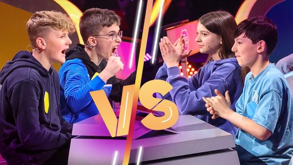 Zwei Teams sitzen sich an Spielpulten gegenüber. Auf der rechten Seite wird in die Hände geklatscht. Das Team links freut sich lautstark.