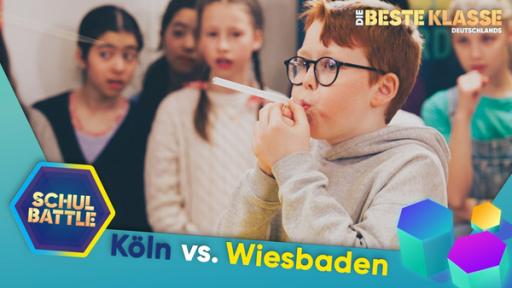 Rechte: KiKA/Bavaria Entertainment Ein Junge pustet mit konzentriertem Blick durch ein Trinkröhrchen, das er waagerecht im Mund hält. Hinter ihm Kinder, die gespannt zuschauen. Unten der Text Köln versus Wiesbaden und das Schulbattle-Logo.