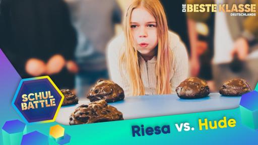 Ein Mädchen beugt sich über einen Tisch, auf dem kleine Häufchen liegen und pustet mit konzentriertem Blick. Unten der Text Riesa versus Hude und das Schulbattle-Logo.