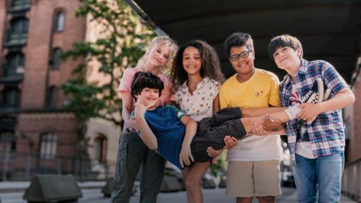 Die Pfefferkörner Malin, Taara, Kofi und Jules tragen gemeinsam Piet. Die Jungen halten seine Beine, die Mädchen seine Schultern.