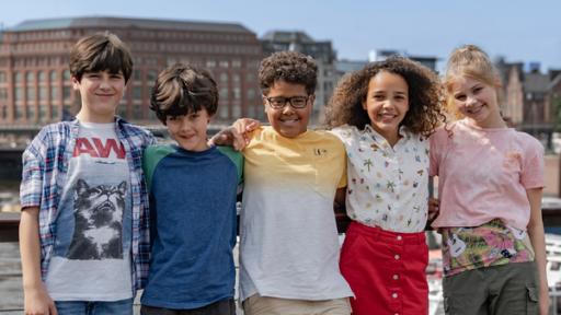 Die Pfefferkörner der vierzehnten Generation | Rechte: Letterbox/NDR Jules, Piet, Kofi, Taara und Malin stehen vor roten Backsteinhäusern.