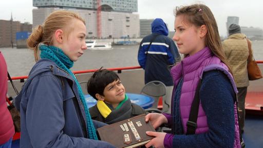 Abschied tut weh | Rechte: NDR/Studio HH Foto: Romano Ruhnau Nina (Carolin Garnier, rechts) übergibt Jessi (Martha Fries, links) und Luis (Emilio Sanmarino, Mitte) das Pfefferkörnerbuch.
