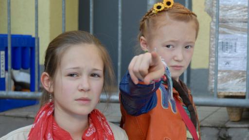 Lina (Lale H. Mann) steht neben Emma (Aurelia Stern), die mit dem Finger auf etwas zeigt.