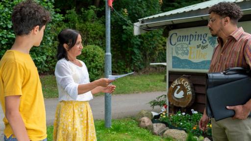 Giftige Fässer | Rechte: NDR/Letterbox - Boris Laewen Tarun und seine Mutter Jaswinder stehen vor dem Eingang zum Campingplatz und überreichen einem Mann einen Zettel.