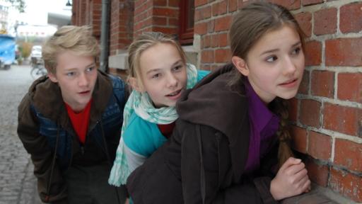 Hauptgericht: Schlange | Rechte: NDR/Studio Hamburg - Romano Ruhnau Max (Bruno Alexander), Jessi (Martha Fries) und Nina (Carolin Garnier) halten sich gedeckt an einer Hauswand.