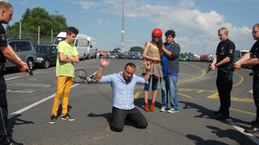 Munition | Rechte: NDR/Studio HH Foto: Romano Ruhnau Der Munitionsschmuggler Thorsten Fricke (Tim Grobe) wird von Polizisten gestellt. Die Pfefferkörner (von links nach rechts: Jaden Dreier, Merle de Villiers und Danilo Kamber) stehen dabei