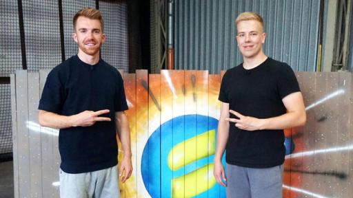 Die Sportmacher - Avive | Rechte: ZDF Stefan (links) steht neben Avive (rechts). Sie machen ein Peace-Zeichen.