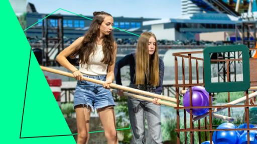 In der Stadt | Rechte: ZDF / Katja Inderka "Earthgame - Die Bodenretter": Die Mitglieder von "Pilzcycling", Zoé und Helena, holen mit langen Stangen Bälle aus einem Gitterkorb.