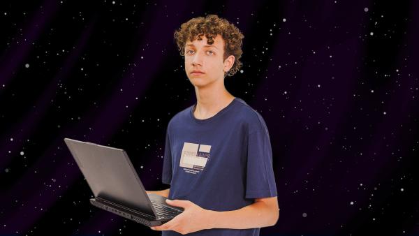 braungelockter Junge hält Laptop in der Hand und schaut verträumt in die Ferne