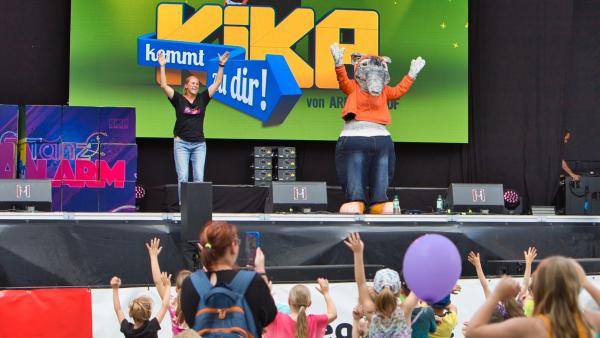 Singa und TanzTapir tanzen auf einer Bühne, davor stehen Kinder