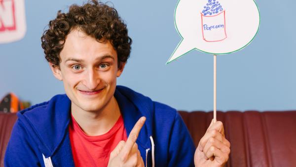 Julian hält ein Schild mit Popcorn hoch.