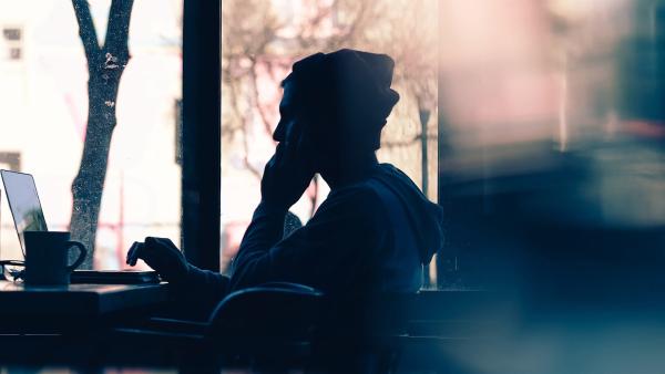 Teenager im Gegenlicht vor Laptop