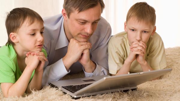 Vater mit zwei Söhnen vorm Laptop