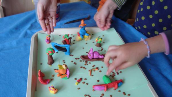 Kinder streuen Linsen über die Fantasiewelt aus Knete.