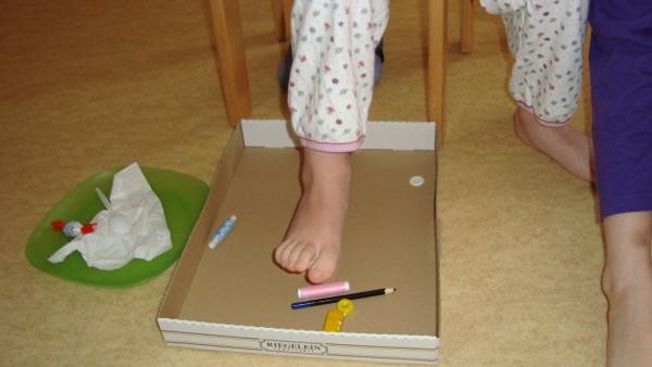 Der Fuß eines Kinds in dem Karton, in dem Gegenstände liegen.