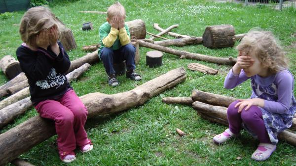 Kinder im Garten halten sich die Augen zu