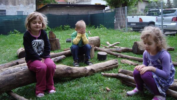 Kinder sitzen mit geschlossenen Augen im Garten.