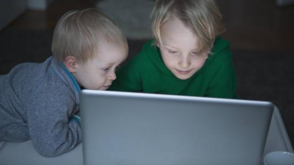 Zwei kleine Kinder schauen auf einen Laptop.