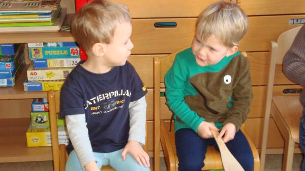 Zwei Jungen trommeln mit Kochlöffeln auf Dosen.