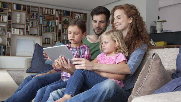 Eine Familie schaut auf ihr Tablet.